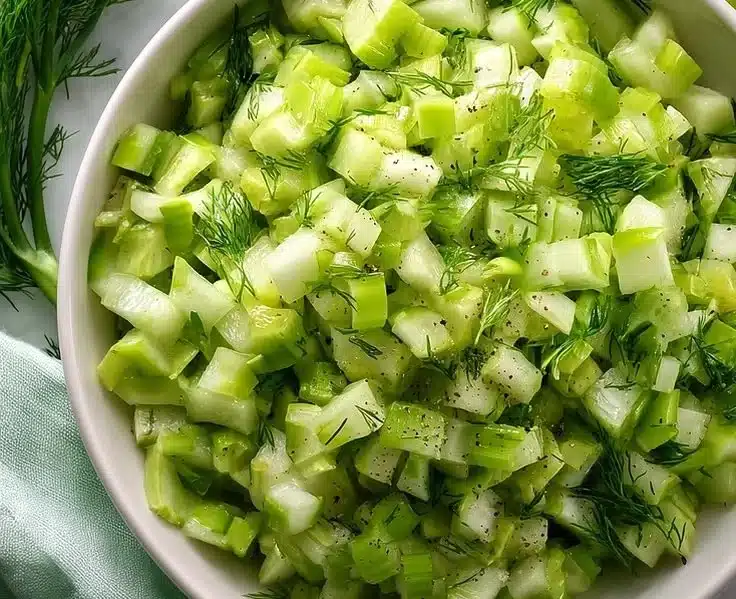 Quick celery salad with dill served in a bowl, garnished with fresh herbs
