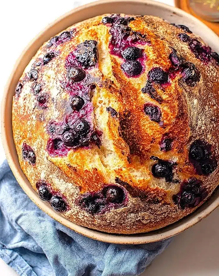 Freshly baked rustic blueberry sourdough bread on a wooden table