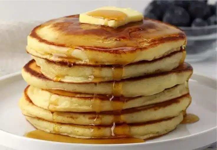 Fluffy classic pancakes served with syrup and berries.